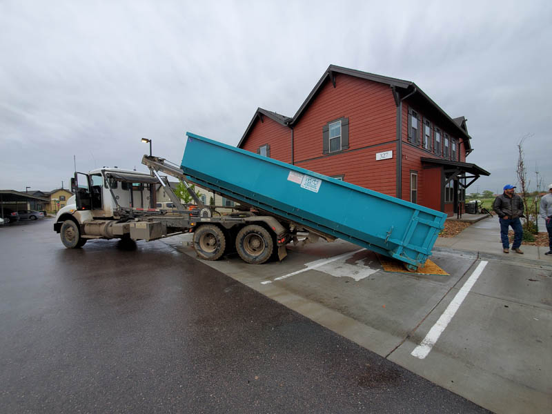 Custom Exteriors replacing a dumpster on multi family roof replacements in Colorado