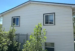 A home in Brush, Colorado with white vinyl siding being inspected by Custom Exteriors.