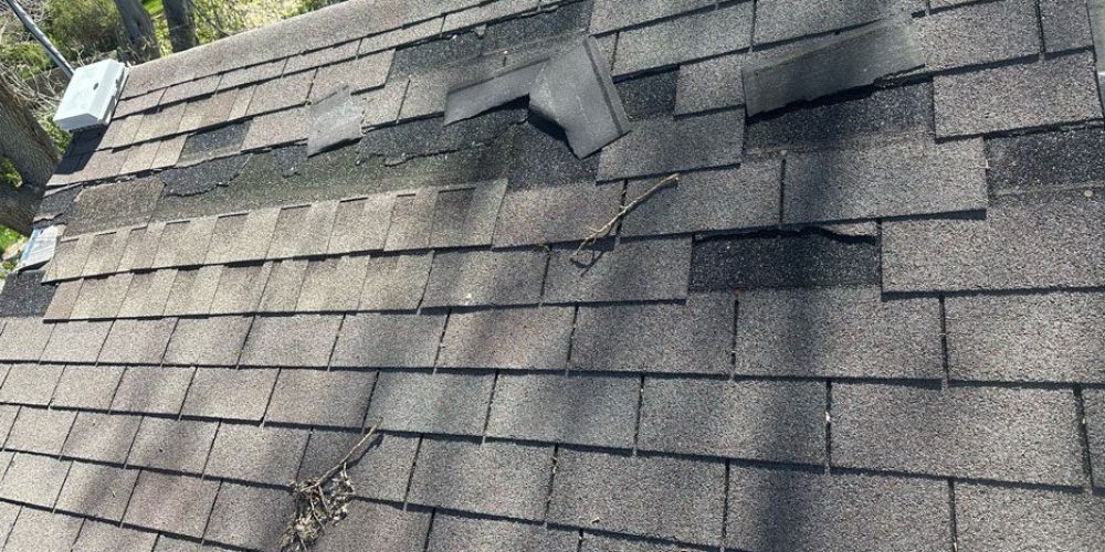 A photo taken during a roof inspection in Northern Colorado by Custom Exteriors showing the lack of wind resistance that three-tab shingles struggle with